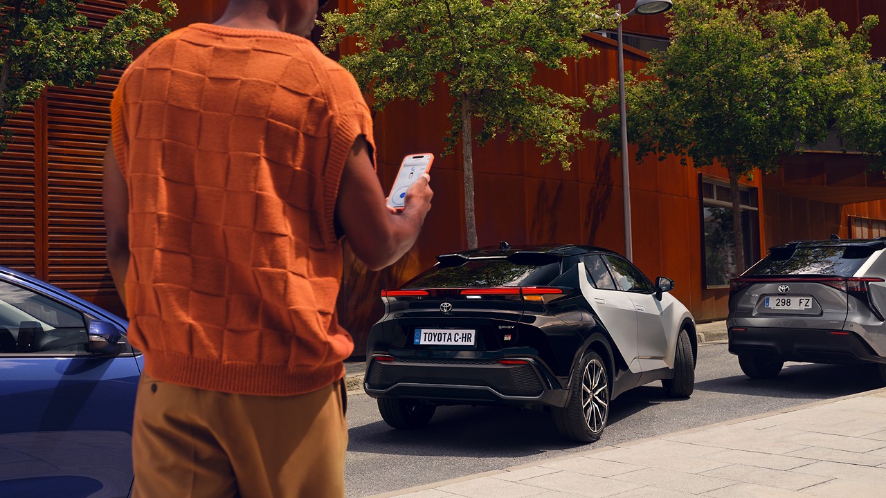 Person, der går mod en Toyota C-HR med telefon