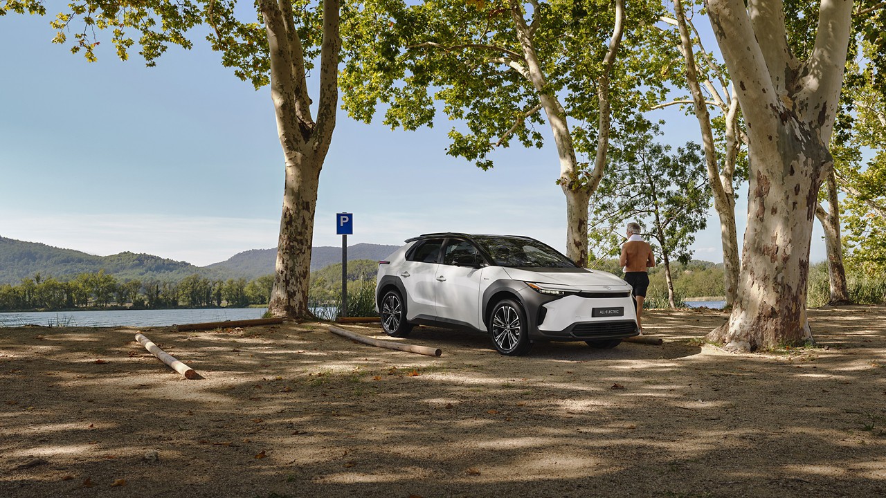 Hvid bz4X parkeret med udsigt over et naturlandskab. Mand stod ved siden af bilen og beundrede udsigten